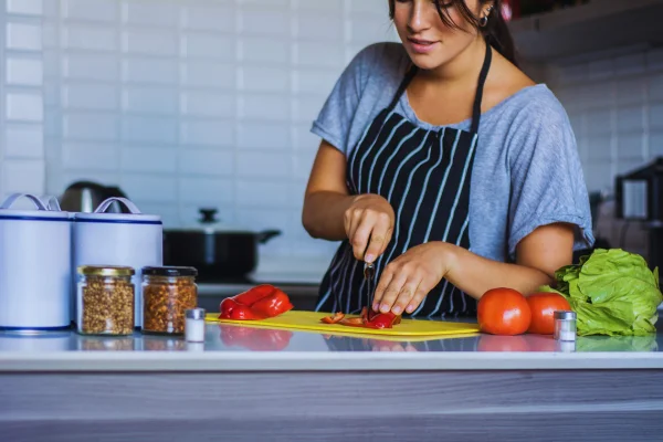 para comer saludable la mujer está cortando pimentones en un fondo de cocina y con verduras sobre la mesa