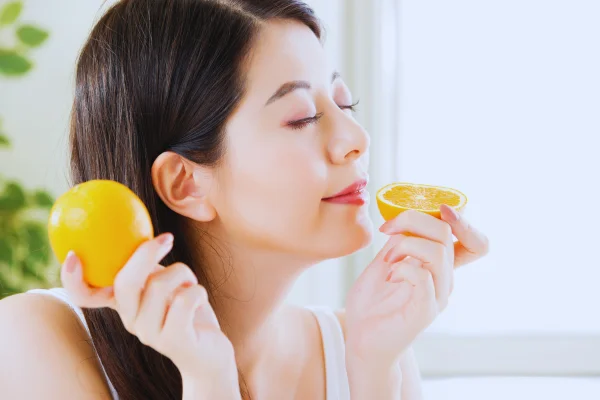 mujer que estimula el olfato con naranja para recuperar el olfato