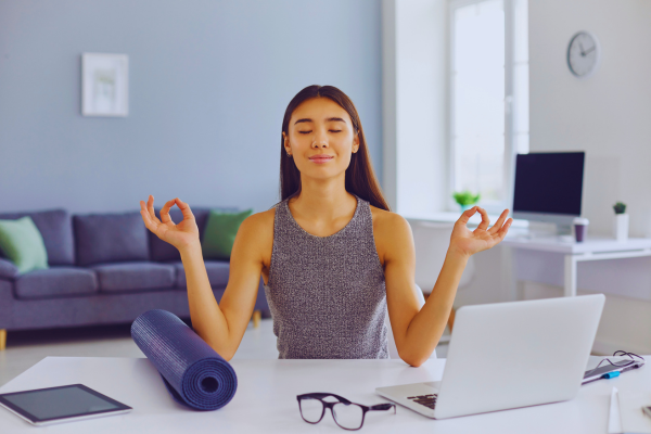 salud mental con mujer meditando en su escritorio durante el trabajo
