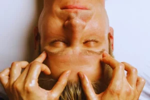 Realizando masaje facial japonés a un hombre