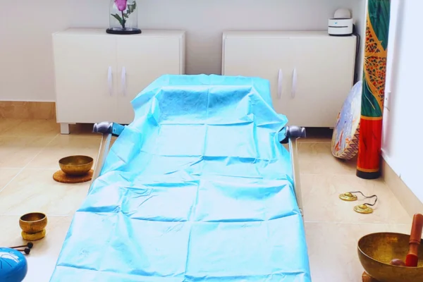 sonoterapia con diversos instrumentos en el piso y al lado de la camilla para la terapia de sonido