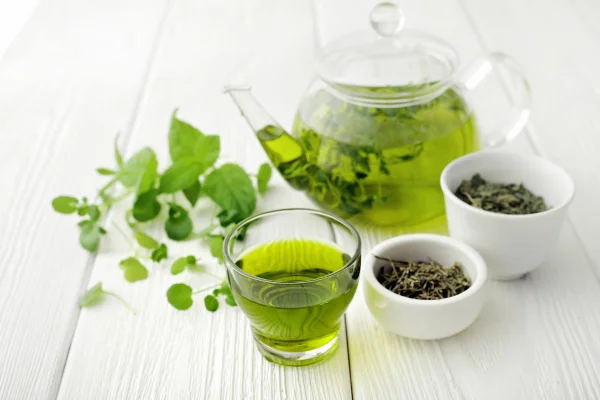 preparacion del te verde para aprovechar sus beneficios donde se observan una tetera con te en hojas secas y un vaso